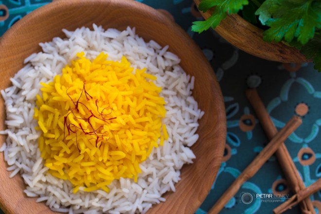 Rice cooked with saffron in a wooden bowl with fresh parsley for garnish